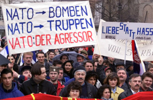 Several thousand Serbs who live in Germany demonstrate Sunday, Feb. 21, 1999, at the Bonn's Muenster Platz against the threats by NATO of airstrikes, if a peace agreement between Serbia and the ethenic Albanias in Kosovo remains elusive. Baner at left reads, " NATO-Bombs, NATO-Troops, NATO: The Agressor", and at right  "Love instead of hate". (AP Photo/Fritz Reiss)